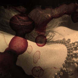 Diamantencollier am Hals einer Frau, darüber Blutflecken in einer Collage. 