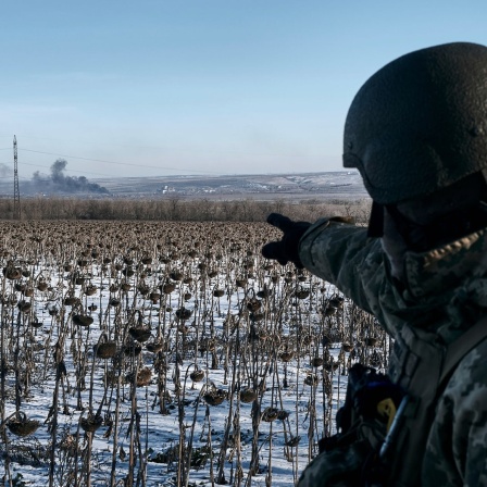 Ein ukrainischer Soldat zeigt auf aufsteigenden Rauch auf seiner Position an der Frontlinie im Donbass in der Nähe der umkämpften Stadt Soledar.