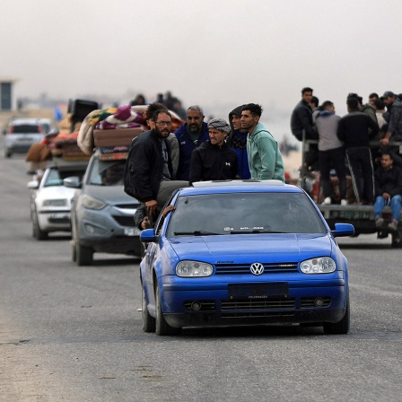 In Rafah im Gazastreifen fahren Menschen mit vollbeladenen und überfüllten Autos auf einer Straße, auch Fußgänger sind zu sehen.