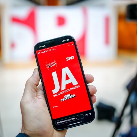Ein Smartphone, auf dessen Bildschirm in Großbuchstaben "JA" steht