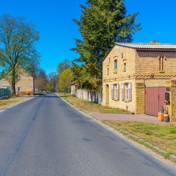 Eine Landstraße, die durch ein Dorf führt. Rechts und links sind alte Häuser zu sehen - Beispiele für historische Dorfarchitektur mit denkmalgeschützte Fassaden.