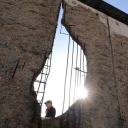 Mann hinter Resten der Berliner Mauer; © dpa/Geisler-Fotopress/K.M. Krause