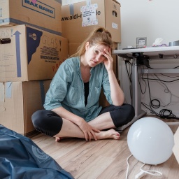 Eine Frau sitzt in einer Wohnung in Hamburg erschoepft zwischen Umzugskartons (gestellte Szene). 