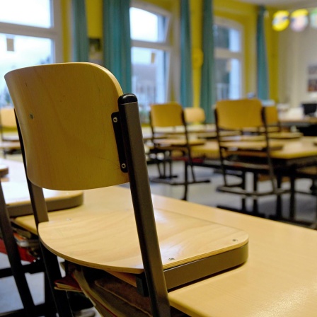 Stühle stehen in einem Klassenzimmer in einer Grundschule auf den Tischen.