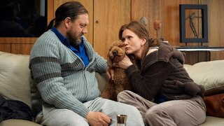Szenenbild aus der Impro-Serie "Kranitz - Bei Trennung Geld zurück": Ein Paar sitz mit einem Hund auf einem Sofa.