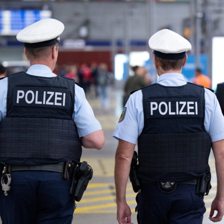 Polizisten gehen durch einen Bahnhof