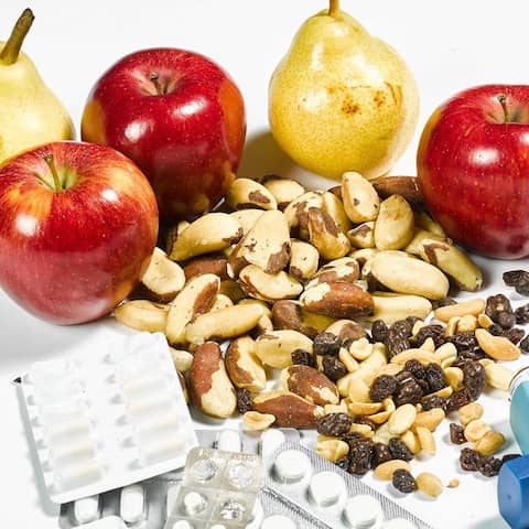 Äpfel, Birnen, Nüsse, Tabletten und Inhalatoren liegen auf einer weißen Fläche.