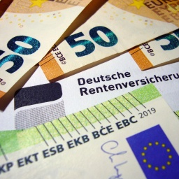 Geldscheine liegen auf einem Brief der Deutschen Rentenversicherung. Es sind 50er und 100er.