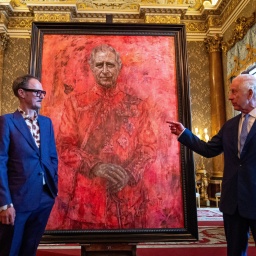 König Charles III. und der britische Künstler Jonathan Yeo (li.) stehen vor dem roten Gemälde des Malers.