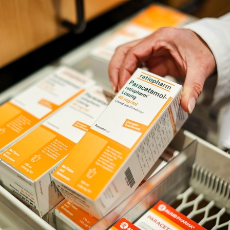 Eine Mitarbeiterin einer Apotheke öffnet ein Schubfach mit Paracetamol Fiebersaft für Kinder.