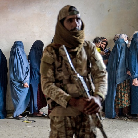 In blauem Stoff (Burka) verhüllte Frauen warten in Kabul in einer Schlange, um von einer humanitären Hilfsorganisation verteilte Lebensmittelrationen zu erhalten