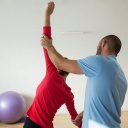 Yogalehrer unterstützt Schülerin bei einer Haltung