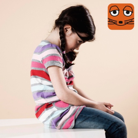 Kind sitzt traurig mit hängenden Schultern