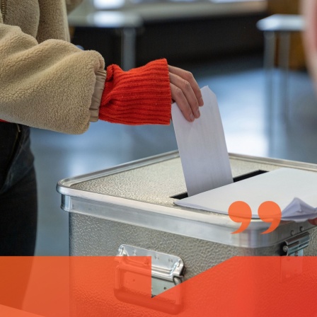 Person gibt Wahlschein in Wahlurne