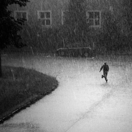 Eine Person rennt bei strömendem Regen. 