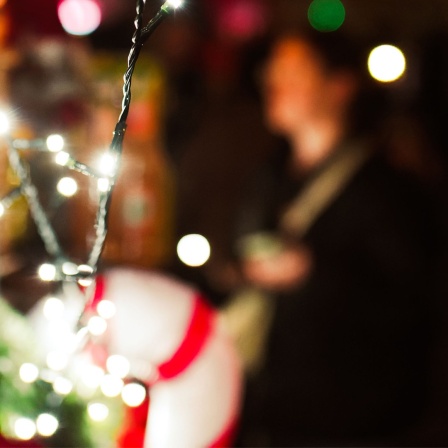 Eine Nahaufnahme von Weihnachtslichtern auf einem Markt mit einem unscharfen Hintergrund mit Menschen.