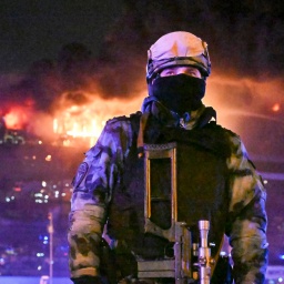 Moskau: Ein Soldat der russischen Nationalgarde (Rosgwardija) sichert ein Gebiet, während über Crocus City Hall am westlichen Rand Moskaus ein gewaltiger Brand zu sehen ist.