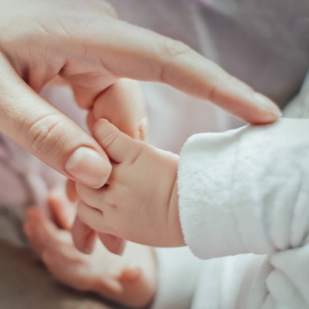 Ein neugeborenes Baby hält die Hand seiner Mutter.