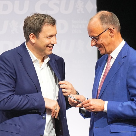CDU-Vorsitzender und -Kanzlerkandidat Friedrich Merz (r) und der SPD-Vorsitzende und designierte Vizekanzler Lars Klingbeil unterhalten sich im Euref-Campus nach der Unterzeichnung des Koalitionsvertrags.