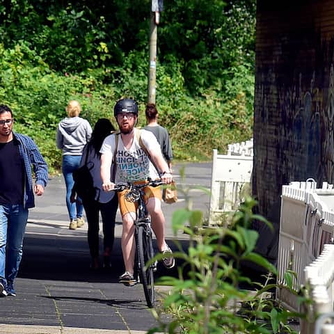 Radfahrer schlängeln sich auf einem gemeinsamen Weg zwischen Fußgängern durch