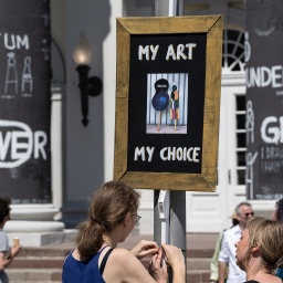 Besucher befestigen auf der documenta fifteen vor dem Museum Fridericianum ein Plakat mit der Aufschrift "My Art My Choice"; © dpa/Swen Pförtner