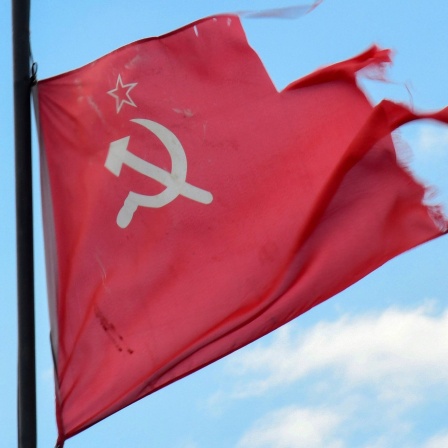 Eine zerfledderte Flagge der früheren Sowjetunion mit Hammer und Sicher auf rotem Grund flattert.