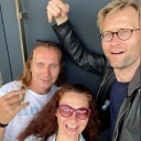 Zwei Männer und eine Frau machen fröhlich ein Selfie