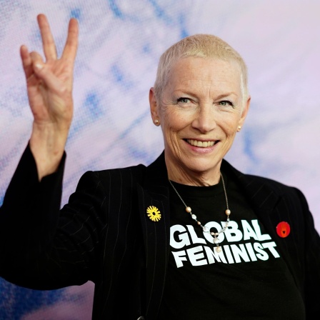 Porträt von Annie Lennox mit Victory-Pose und T-Shirt: "Global Feminist"