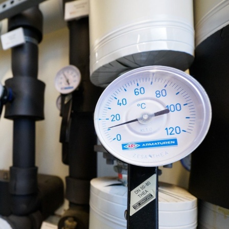 Wärmepumpen-Anlage mit Rohren und Thermostat-Anzeige in einem Heizungsraum 