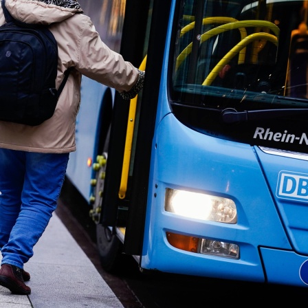 Eine Frau steigt an einer Bushaltestelle in einen Bus ein