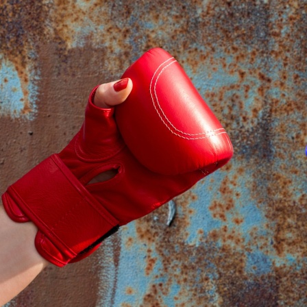 Zwei Hände in einem roten und einem blauen Boxhandschuh.