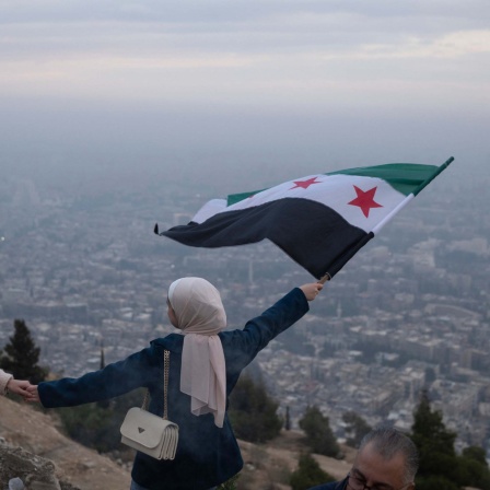 Eine junge Frau posiert für ein Foto mit einer syrischen "Revolutions"-Flagge an einem Aussichtspunkt auf dem Berg Qasiyun oberhalb der Stadt Damaskus. 