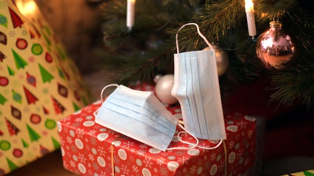 Geschenke und medizinische Schutzmasken unter einem Weihnachtsbaum