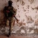 Ein Soldat vor einer von Schüssen zerstörter Wand