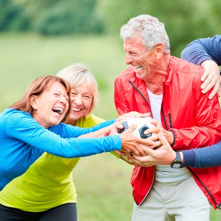 Eine Gruppe Senioren spielt mit einem Fußball im Park