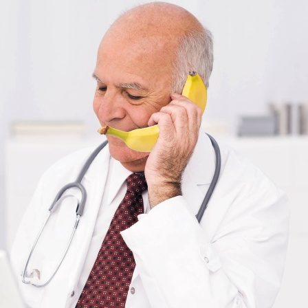 Alter Arzt telefoniert mit Banane