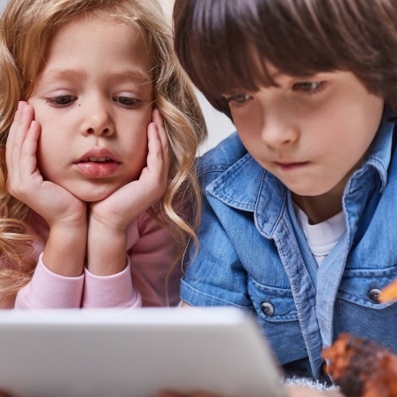 Zwei Kinder mit besorgten Blicken vor einem Tablet