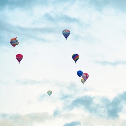 Viele bunte Heißluftballons fliegen in der Luft.