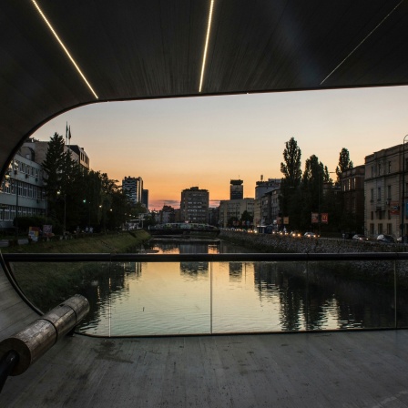 Blick durch den Bogen der Festina Lente Brücke auf Fluss Miljacka bei Dämmerung in Sarajevo.