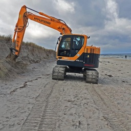 Nach der schweren Sturmflut vom 20. und 21.Oktober 2023 werden die Schaeden sichtbar - ein Bagger glättet die beschädigten Dünen am Ostseestrand in Zingst.