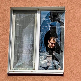 Ein Mann betrachtet das zerbrochene Fenster seines Hauses nach dem Beschuss durch die Ukraine