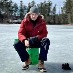 Ingo Zamperoni sitzt in den USA zusammen mit Coach auf einem zugefrorenen See und angelt in einem ins Eis geschlagenen Loch.