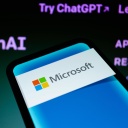 Ein Smartphone mit Microsoft-Logo vor einen ChatGPT-Hintergrund.