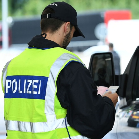 Polizist überprüft einen Fahrer an der deutsch-österreichischen Grenze (Bild: picture alliance/dpa/Revierfoto)