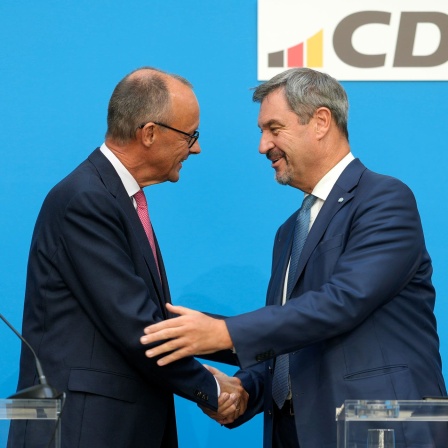 Friedrich Merz und Markus Söder schütteln einander die Hand auf einer Pressekonferenz.