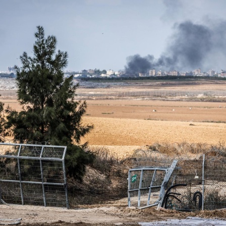 Blick auf ein zerstörtes Tor im Grenzzaun zwischen dem israelischen Kibbuz Kfar Aza und dem Gazastreifen. Im Hintergrund eine Rauchsäule.