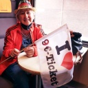 Frau unterstützt mit Fahne und Hut im Zug sitzend das 9-Euro-Ticket