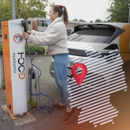 Junge Frau steht an einer E-Auto-Ladestation in Goch. 