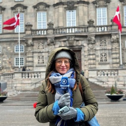 Annelie Malun steht mit Mikrofon in der Hand vor dem Schloss Christiansborg in Kopenhagen.