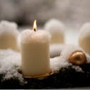 Eine Kerze brennt auf einem schneebedeckten Adventskranz